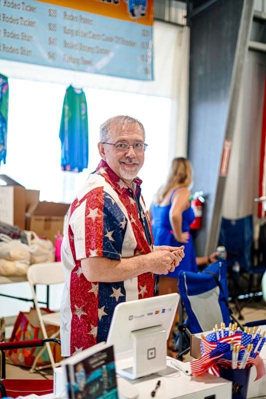 A man in an american flag shirt is standing in front of a counter.