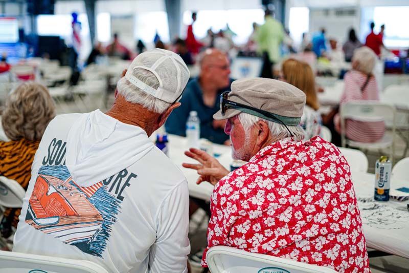 Two men are sitting at a table talking to each other.