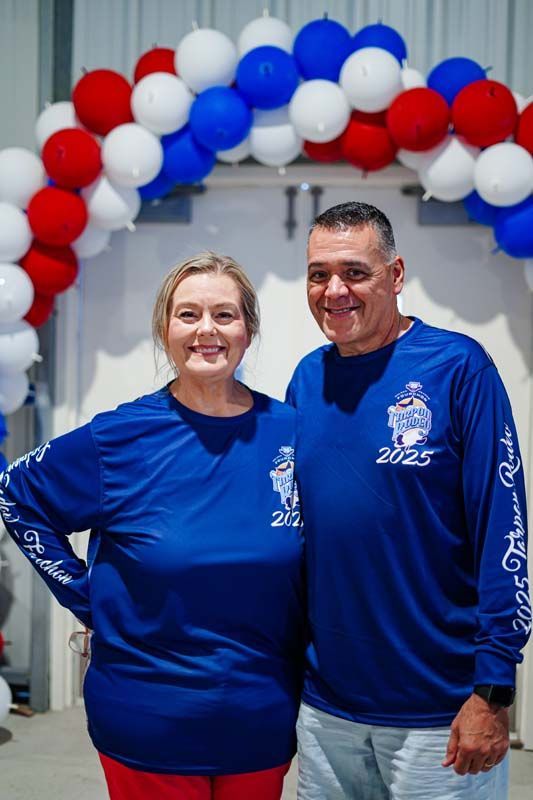 A man and a woman are standing next to each other in front of balloons.