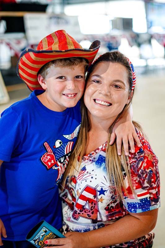A woman and a boy are posing for a picture . the boy is wearing a cowboy hat.