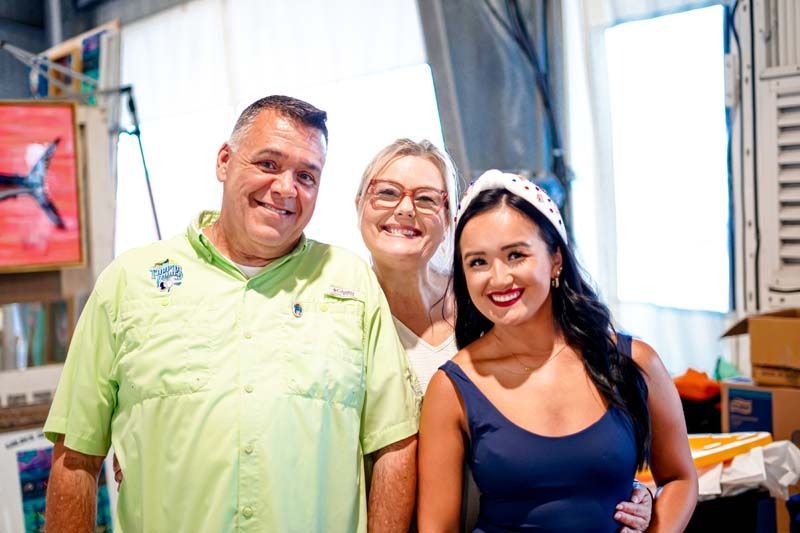 A man and two women are posing for a picture in a room.