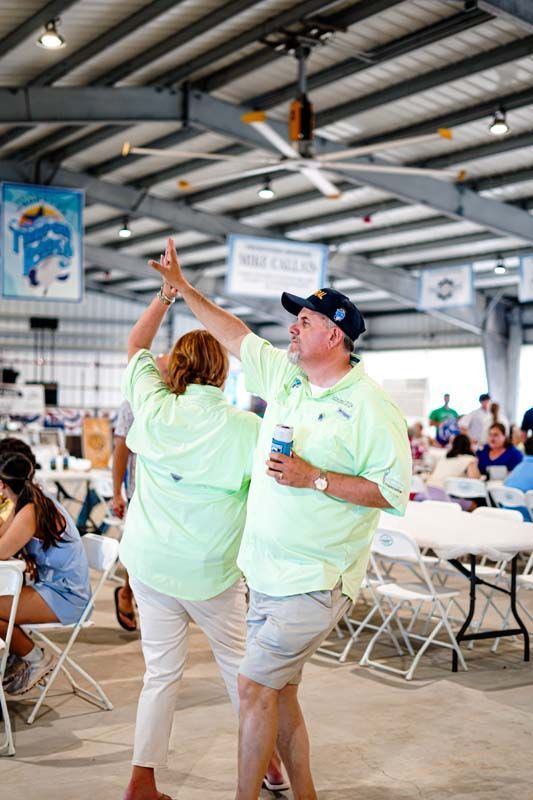 A man and a woman are dancing in a room with tables and chairs.
