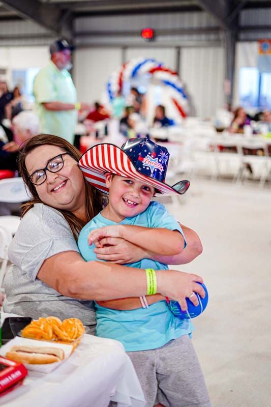 A woman is hugging a little boy who is wearing a hat.