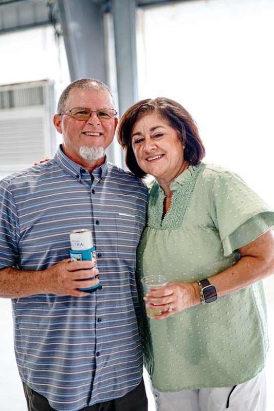 A man and a woman are posing for a picture while holding drinks.