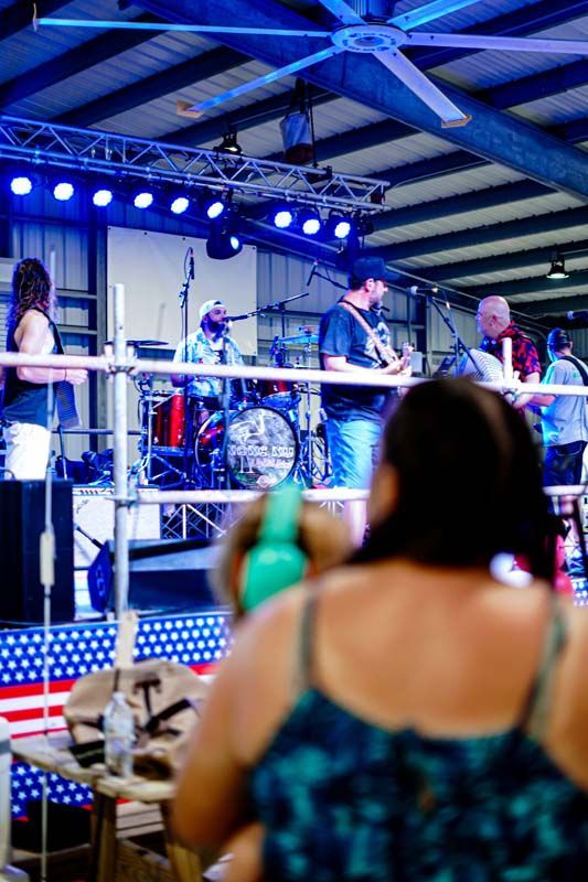 A group of people are sitting in front of a stage watching a band perform.