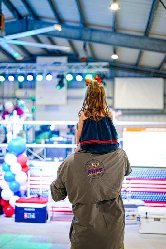 A man is carrying a little girl on his shoulders.