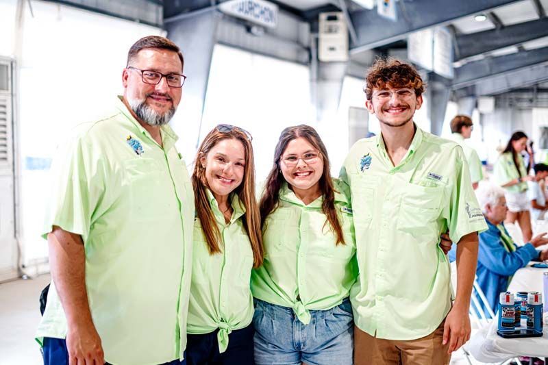 A group of people wearing green shirts are posing for a picture.