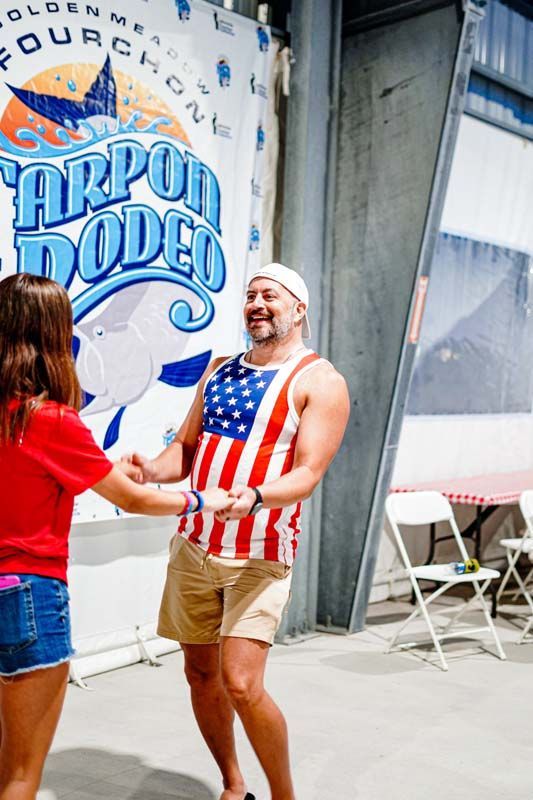 A man in an american flag tank top is dancing with a woman.
