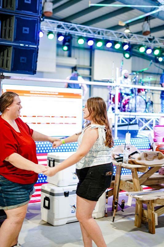Two women are dancing in a room in front of a stage.