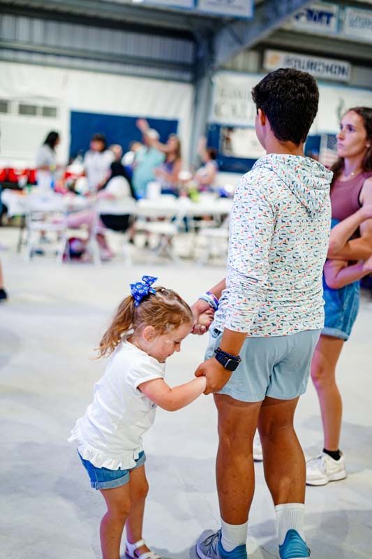 A man and a little girl are holding hands in a gym.