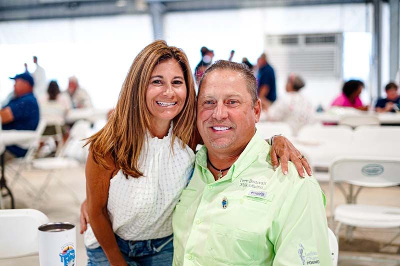 A man and a woman are posing for a picture at a picnic table.