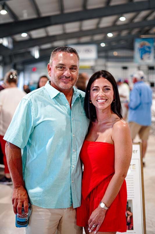 A man and a woman are posing for a picture together . the woman is wearing a red dress.