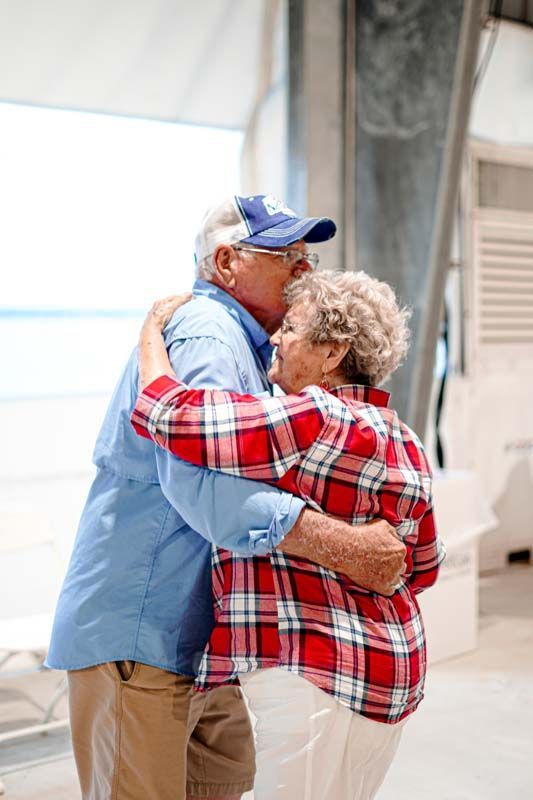 An elderly couple hugging each other in a room.