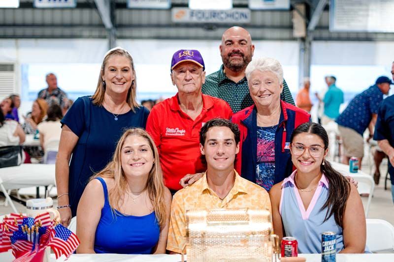 A group of people are posing for a picture in front of a cake.