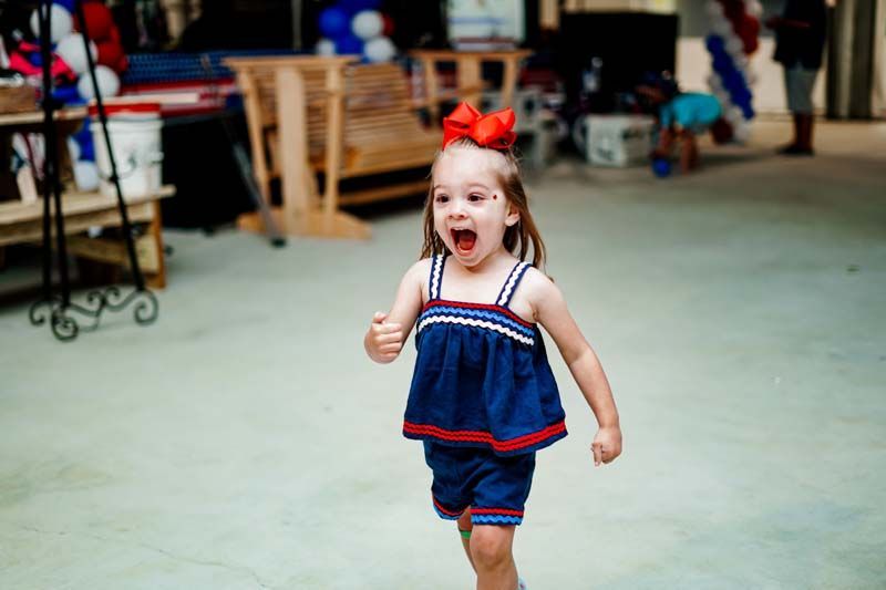 A little girl is running in a room with her mouth open.