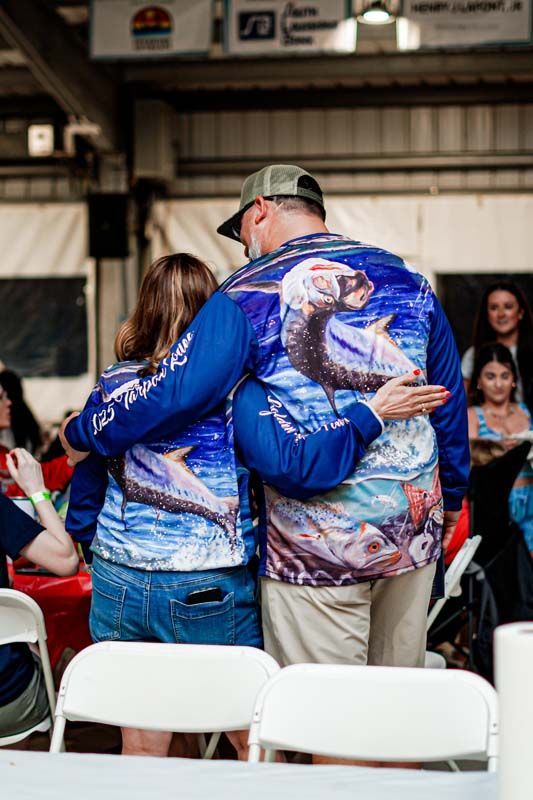 A man and a woman are hugging each other while wearing matching shirts.