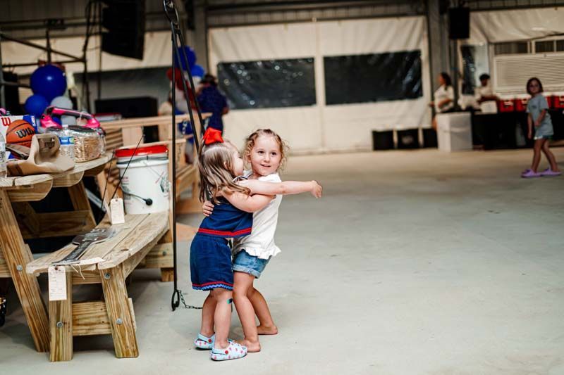 Two little girls are hugging each other in a room.
