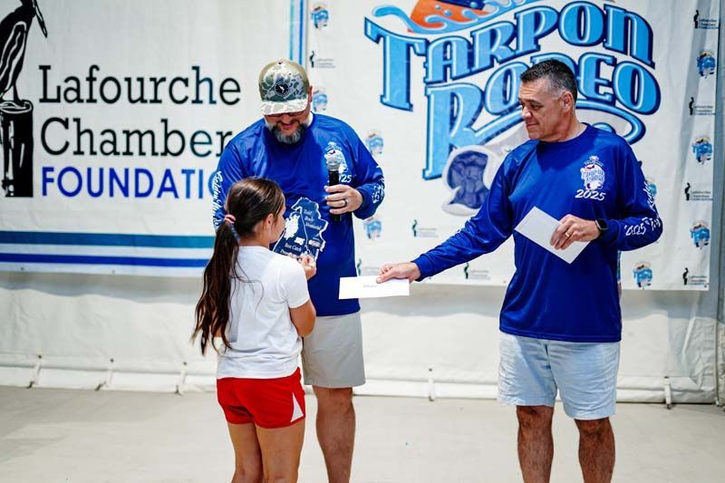 Two men and a girl are standing in front of a sign that says lafourche chamber foundation
