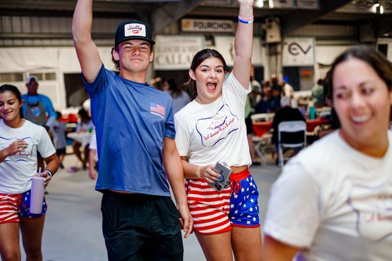 A group of people are standing in a room with their arms in the air.