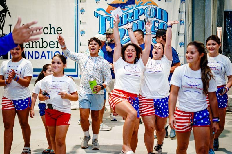 A group of young girls are dancing in front of a sign that says amber foundation.
