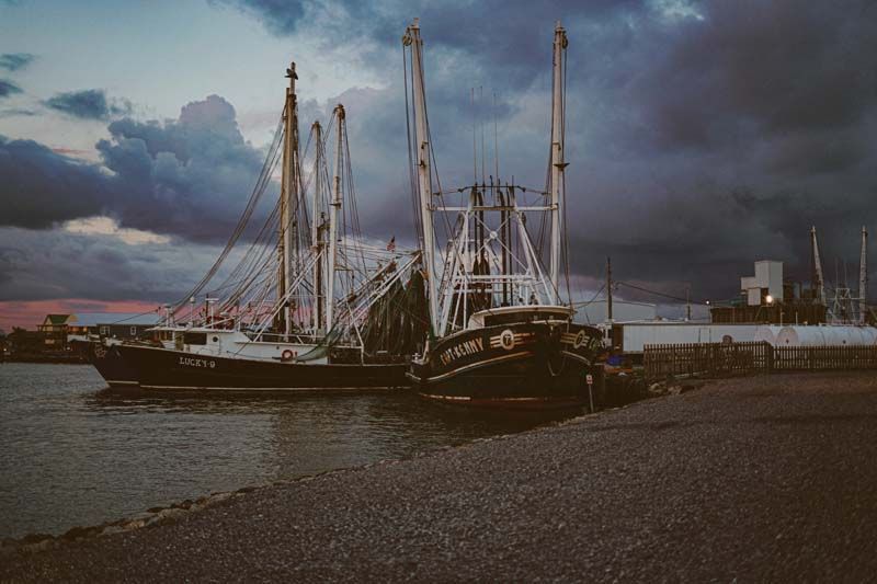 A group of boats are docked in a harbor on a cloudy day.