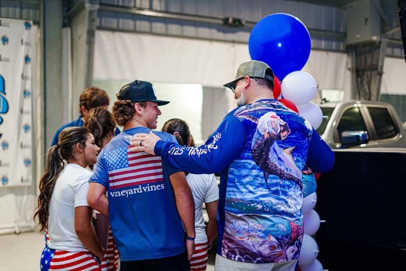 A group of people are standing around a man holding an american flag.