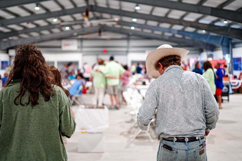 A man in a cowboy hat is standing in front of a crowd of people.