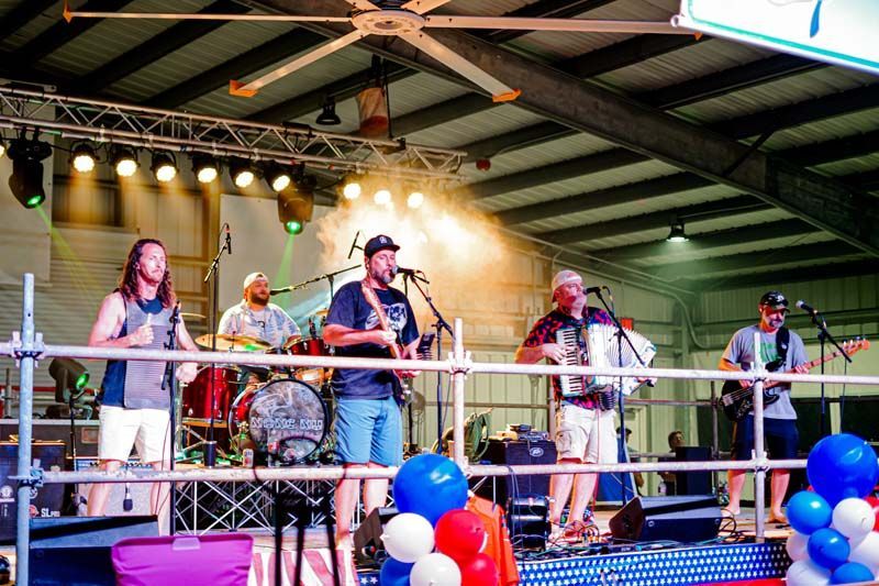 A group of men are standing on a stage playing instruments and singing into microphones.