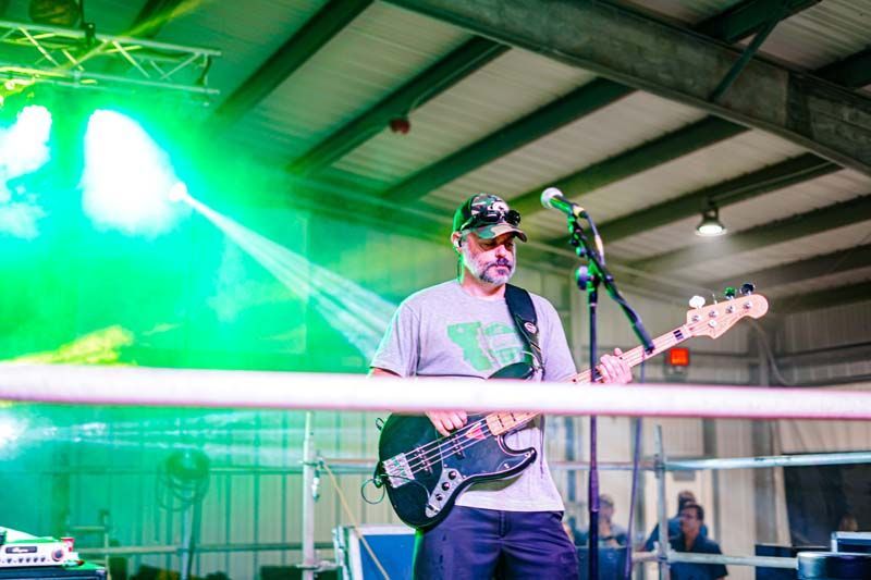 A man is playing a guitar and singing into a microphone on a stage.