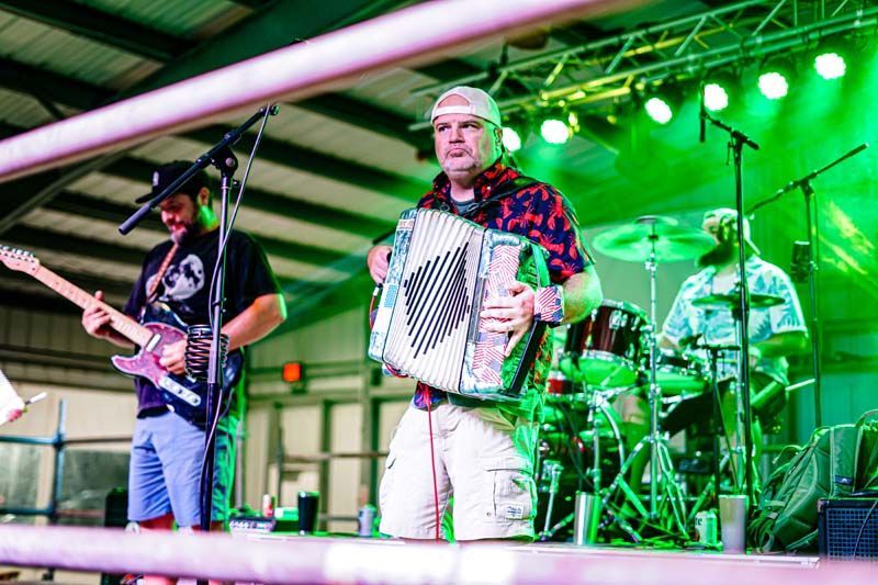 A man is playing an accordion on a stage while another man plays a guitar.