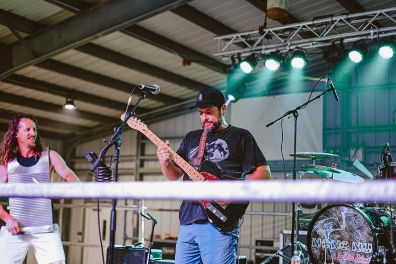 A man is playing a guitar on stage while a woman sings into a microphone.