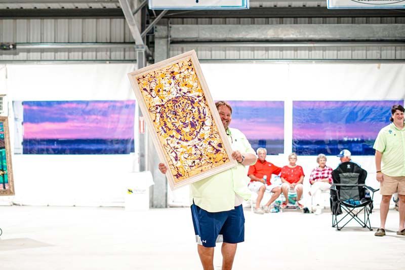 A man is holding a large painting in front of his face.