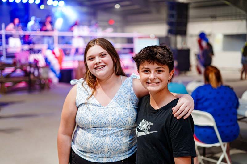 A boy and a girl are posing for a picture in a room.
