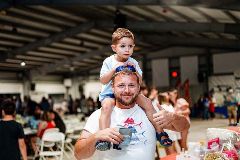 A man is carrying a little boy on his shoulders.