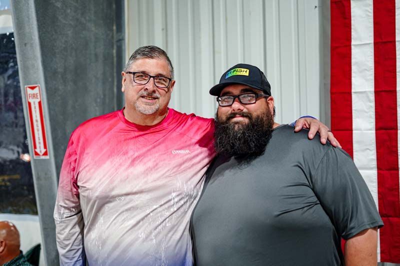 Two men are posing for a picture together in front of an american flag.
