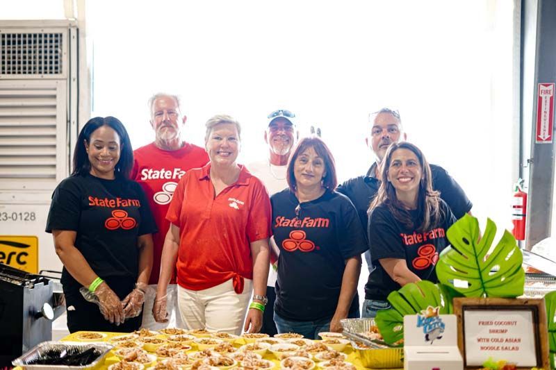 A group of people are posing for a picture in front of a table of food.