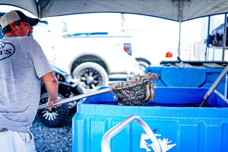 A man is standing in front of a blue bin holding a shovel.