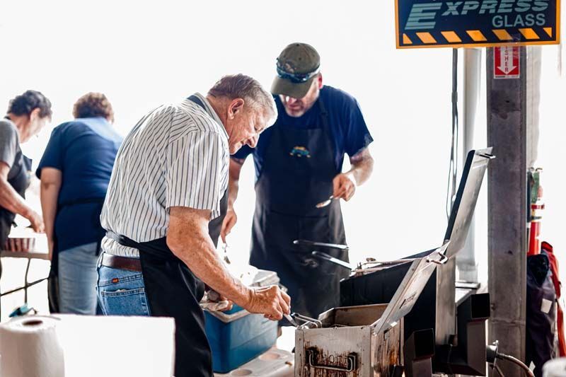 Two men are cooking in front of a sign that says express glass