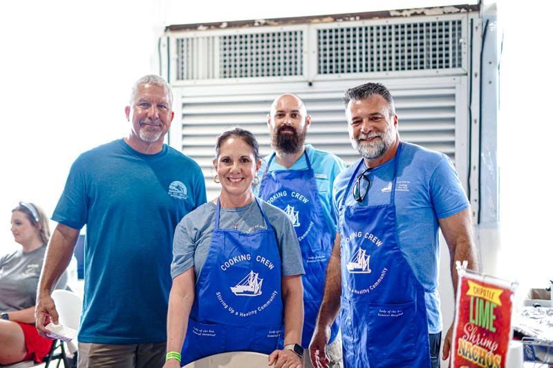 A group of people wearing blue aprons are posing for a picture.