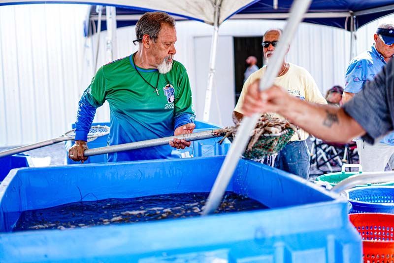 A group of men are standing around a large blue tub of water.