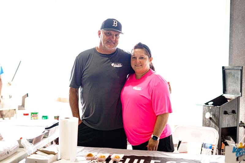 A man and a woman are posing for a picture in front of a table.