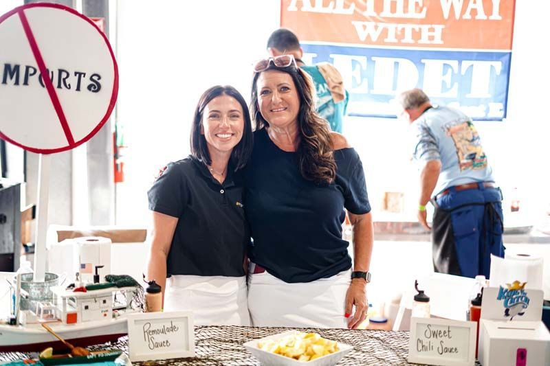 Two women are standing next to each other in front of a table.