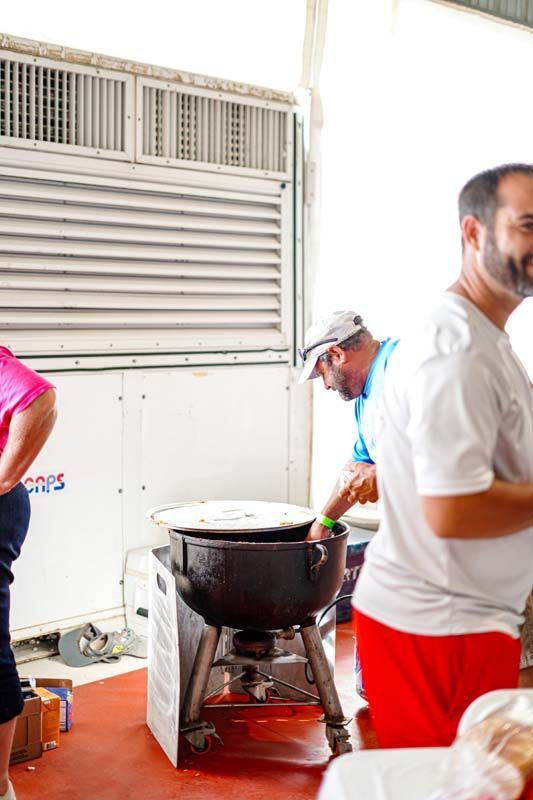 A group of people are standing around a large pot in a room.
