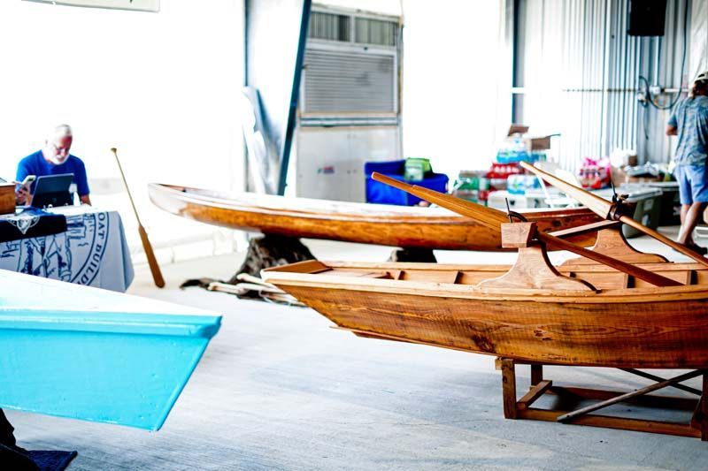 A group of wooden boats are sitting in a warehouse.