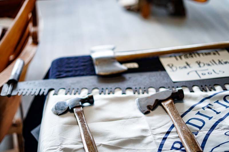 Three hammers are sitting on a table next to a sign that says traditional boot builder tools