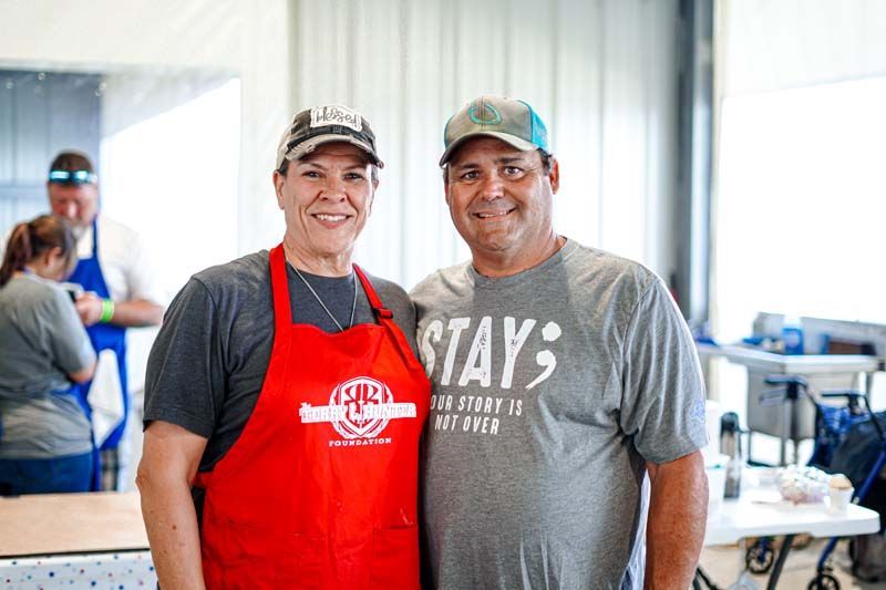 A man and a woman wearing aprons are posing for a picture.