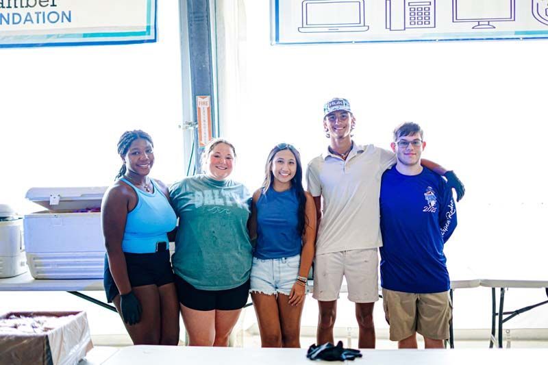 A group of young people are posing for a picture in front of a table.