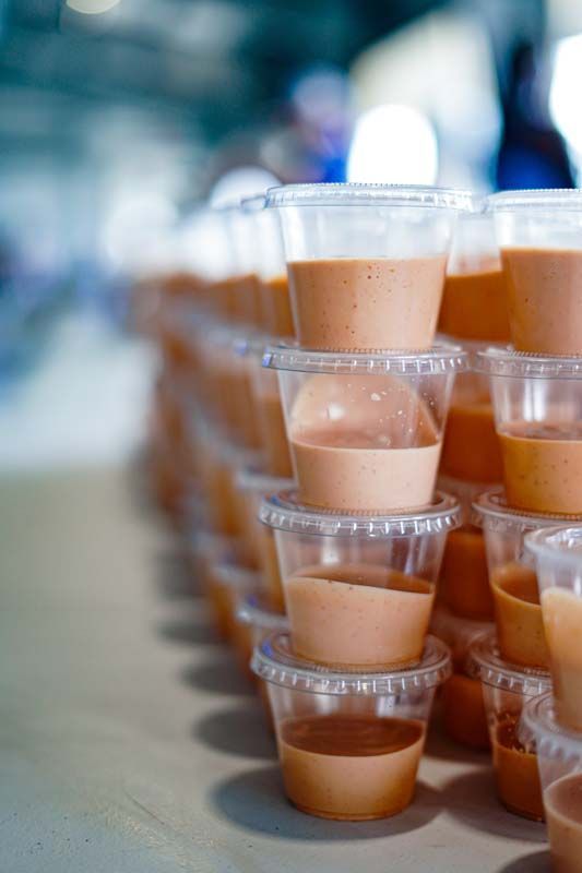 A row of plastic cups filled with sauce are stacked on top of each other on a table.