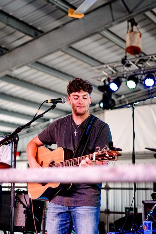 A man is playing a guitar and singing into a microphone on a stage.
