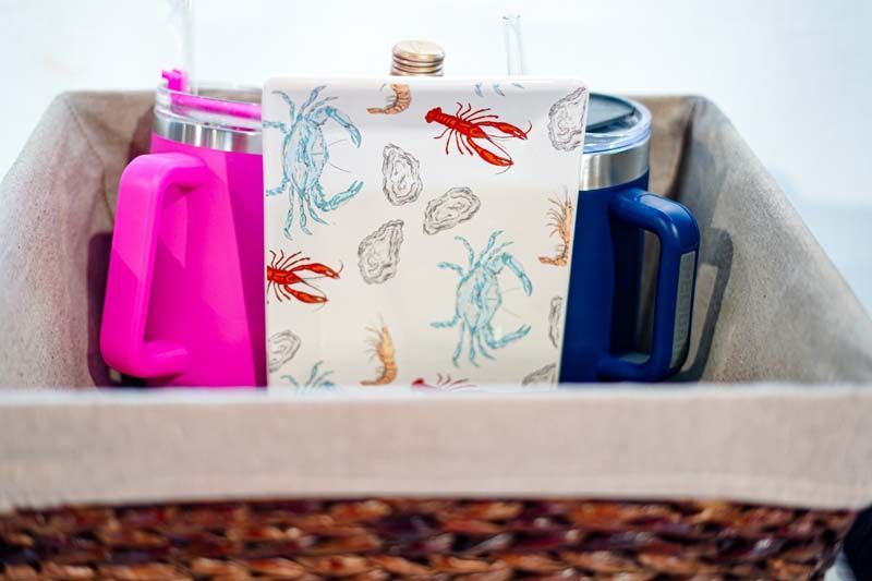 A basket filled with bottles , cups , and a napkin.